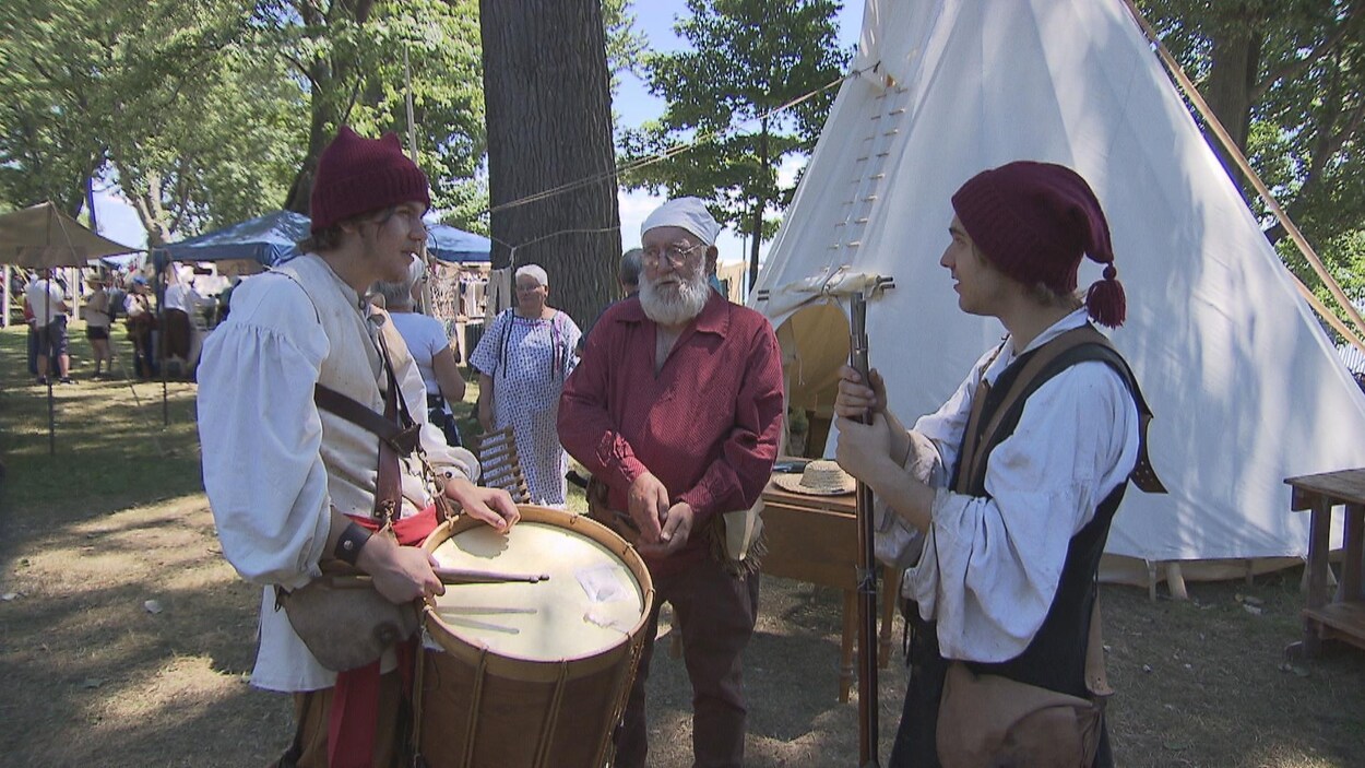 Trois hommes discutent alors qu'ils portent des vêtements de l'époque de la Nouvelle-France. Trois hommes discutent alors qu'ils portent des vêtements de l'époque de la Nouvelle-France.