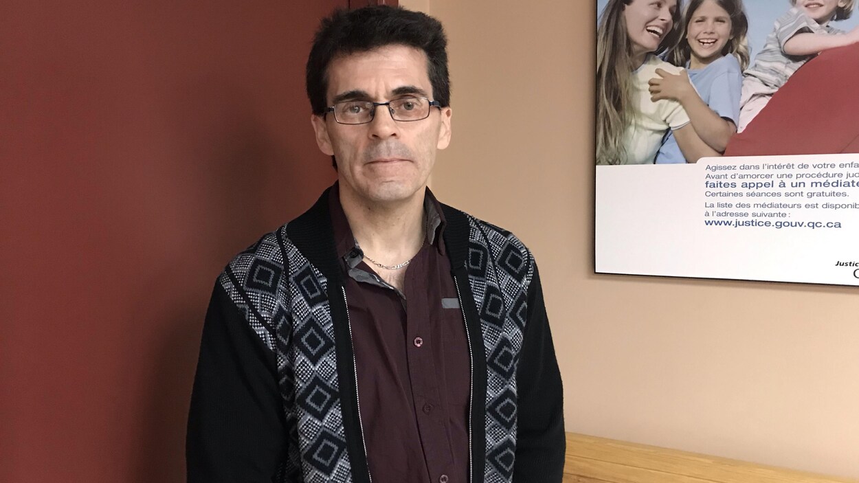 Un homme sourit à la caméra devant une salle du palais de justice de La Sarre.
