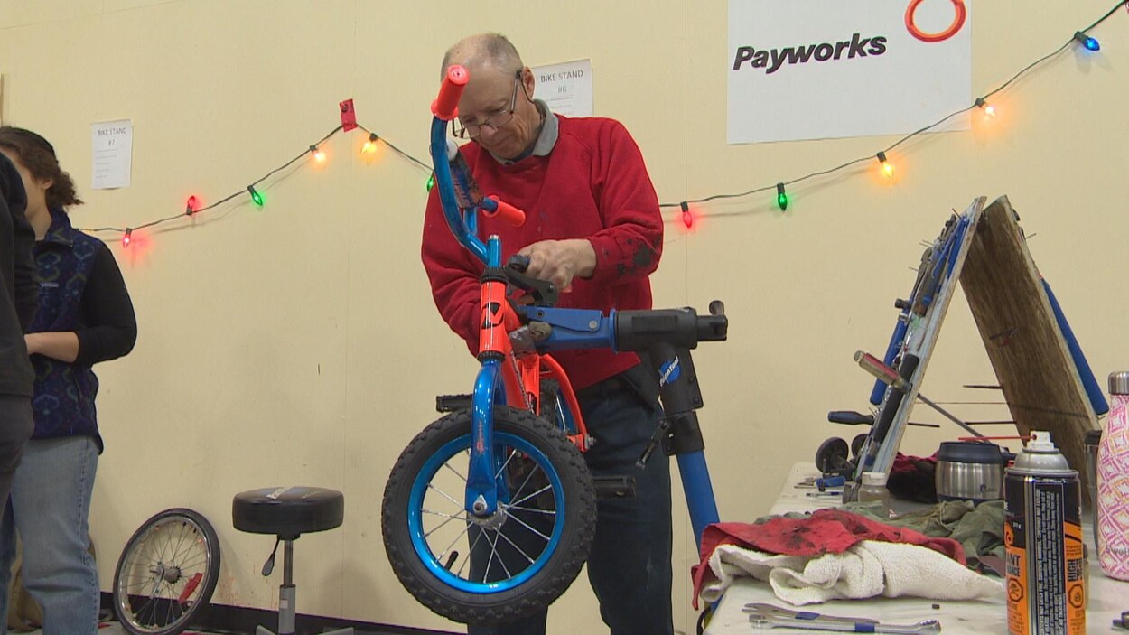 Un homme répare le guidon d'un vélo d'enfant.