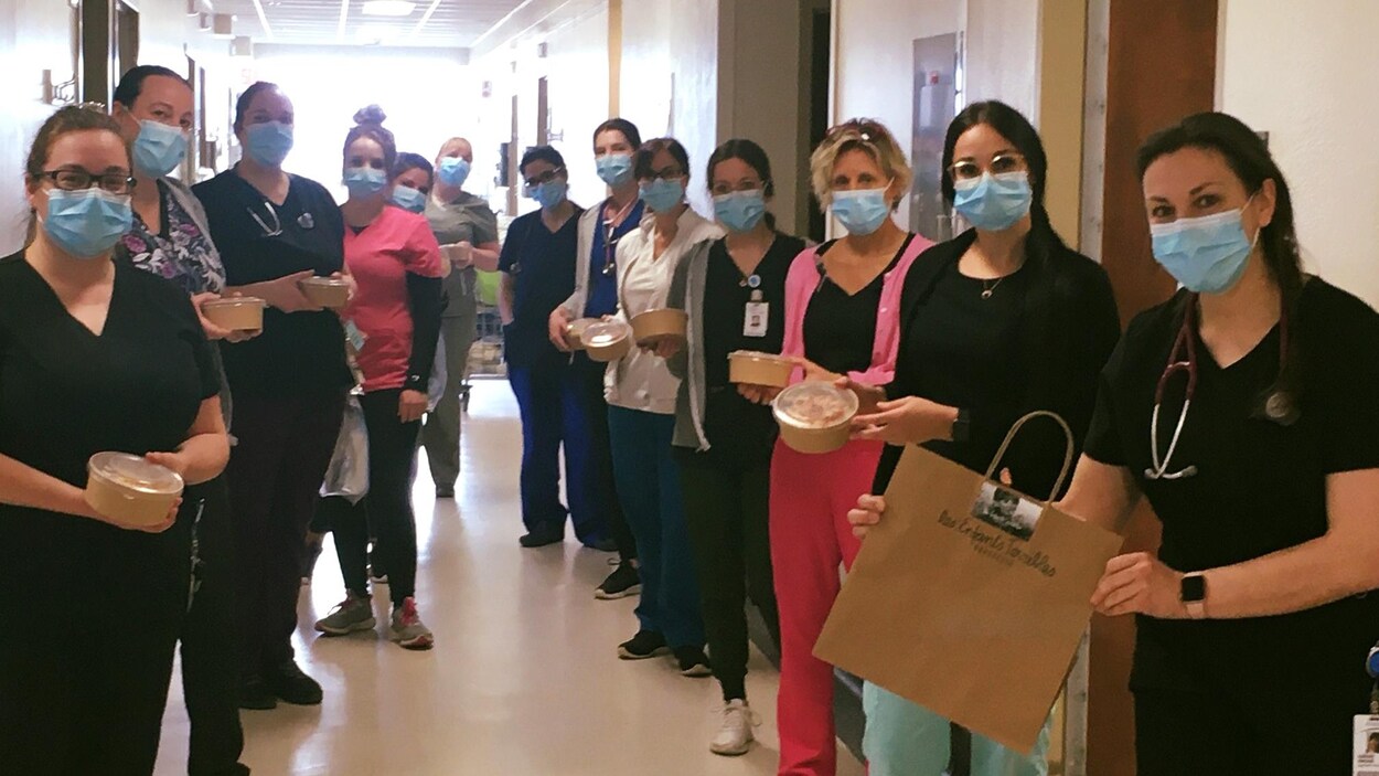 Dans un couloir, des employés, masqués, tiennent les repas livrés par les Enfants terribles.