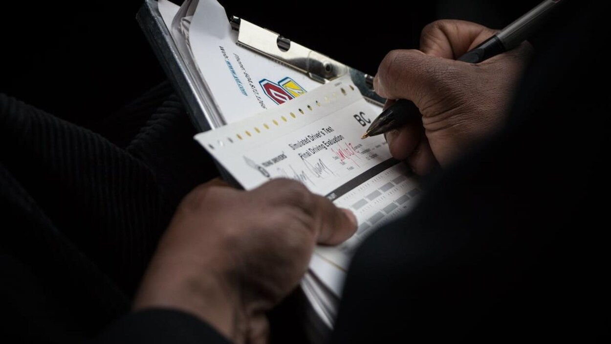 Un évaluateur prend des notes pendant un examen pratique.