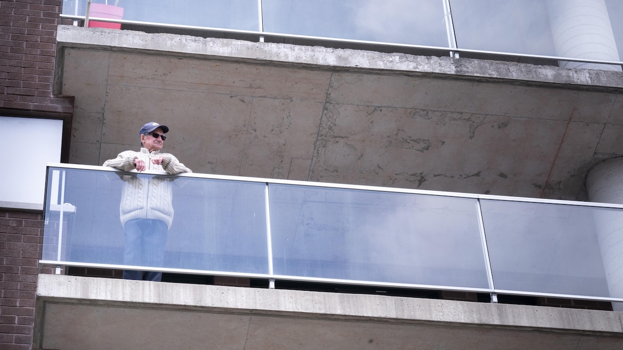 Un homme âgé sur son balcon.