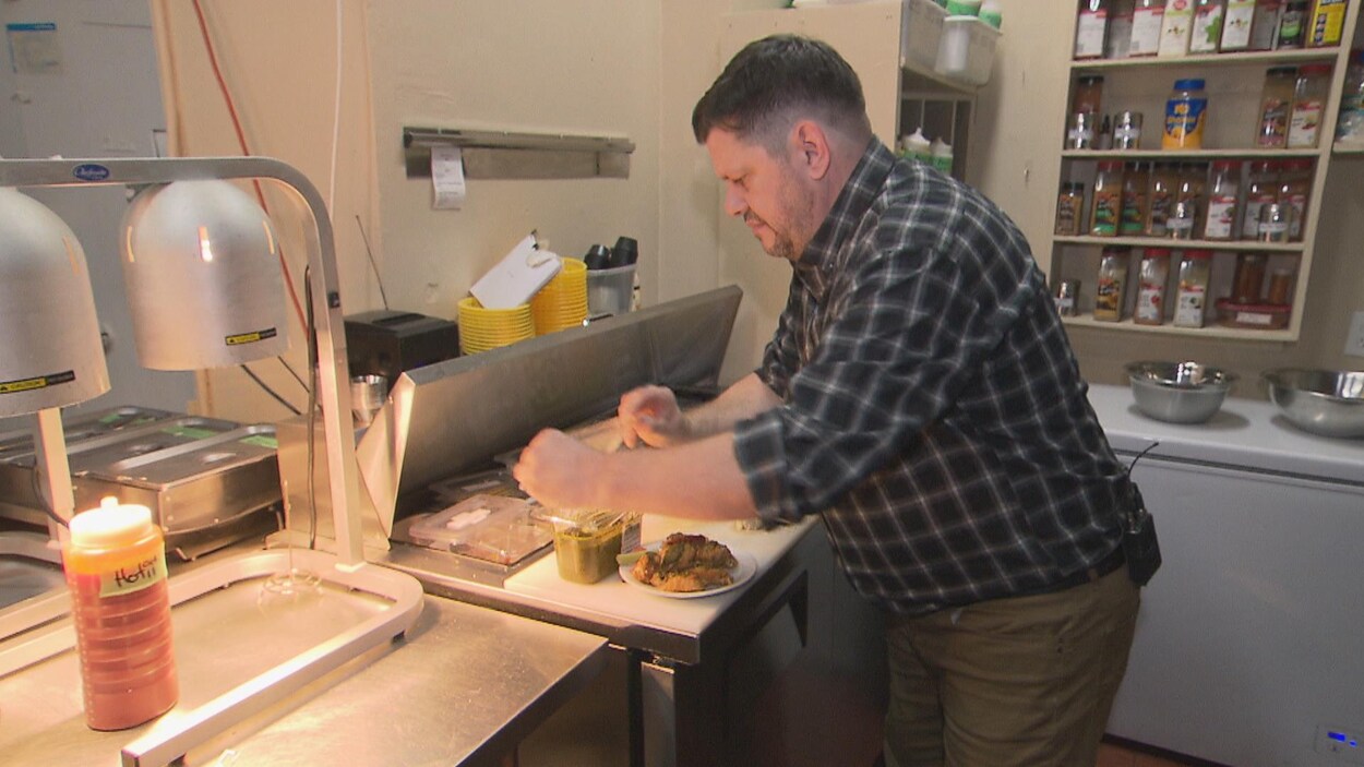 Un homme dans une cuisine industrielle prépare des ailes de poulet.
