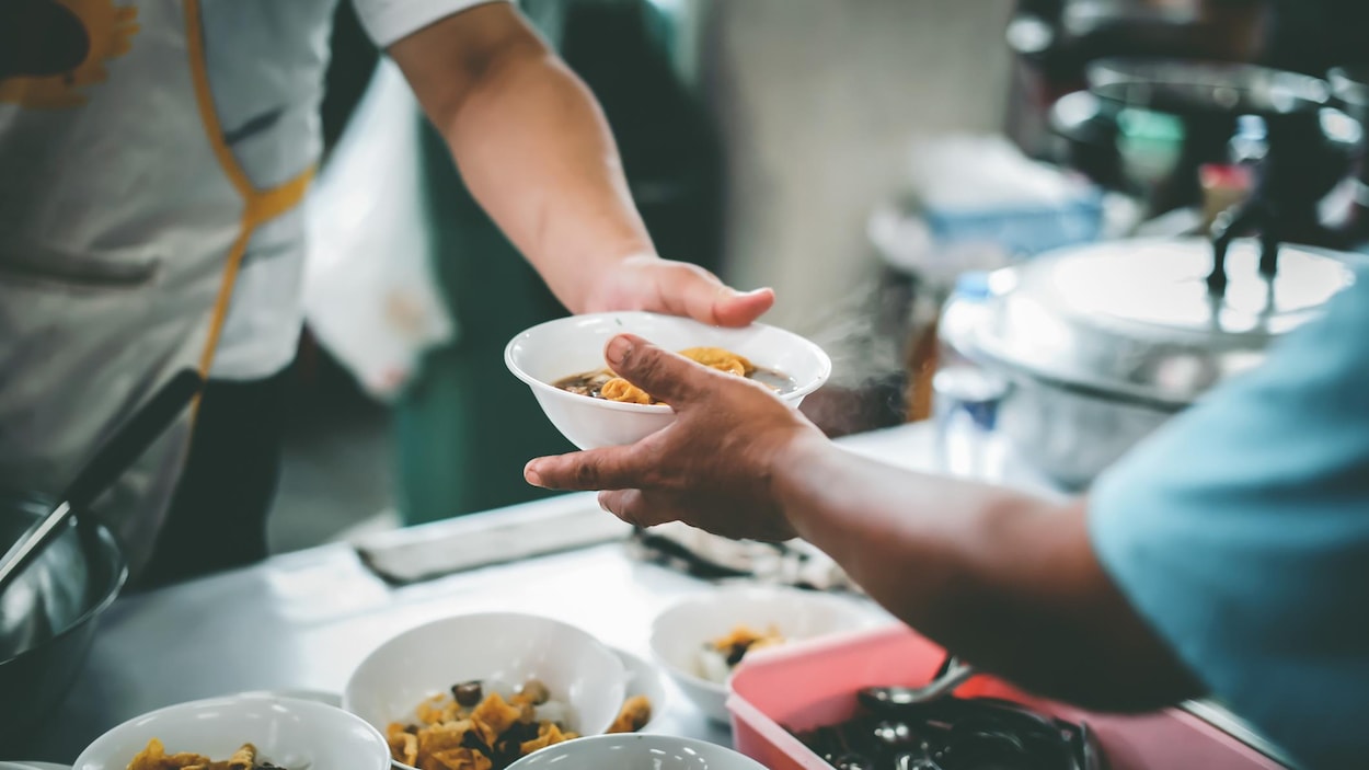 Une personne donne un plat à travers la passe d'un restaurant.