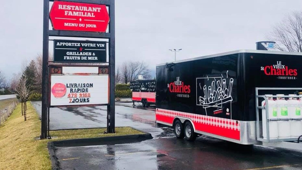 Un camion de cuisine de rue, devant la pancarte du restaurant.