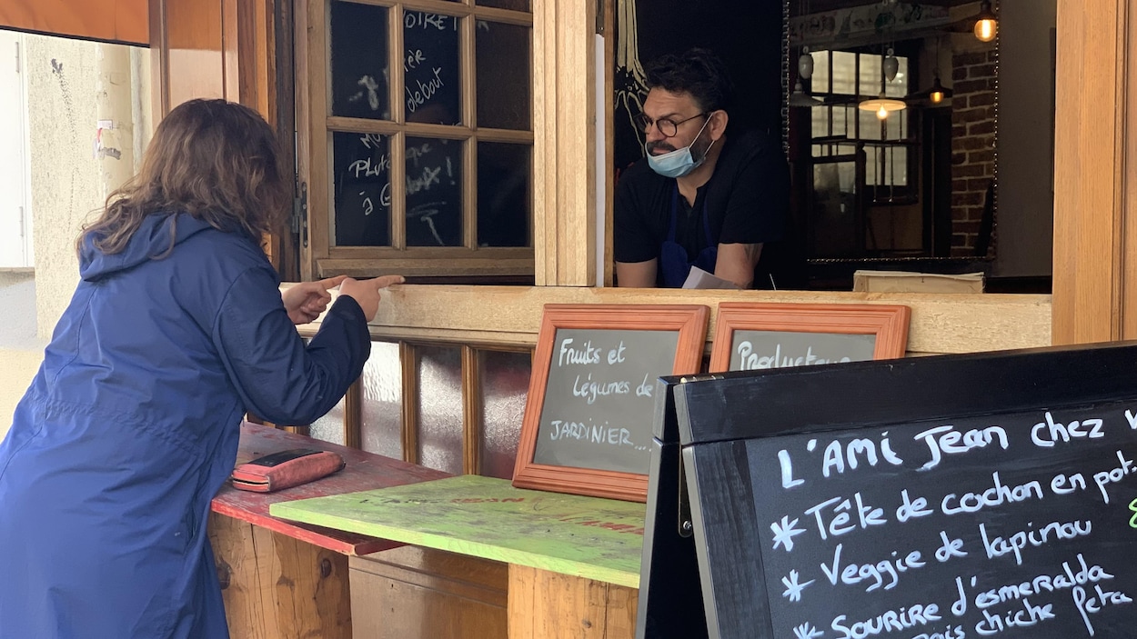 Il discute à travers une fenêtre avec une cliente.