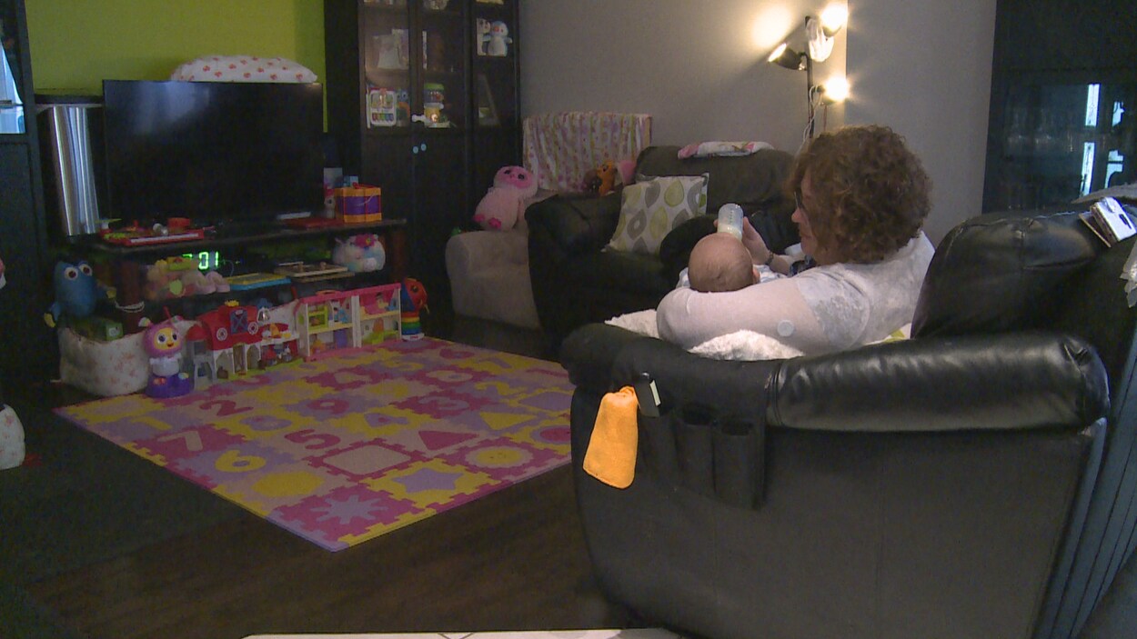 Une mère qui donne le biberon à son enfant dans son salon.