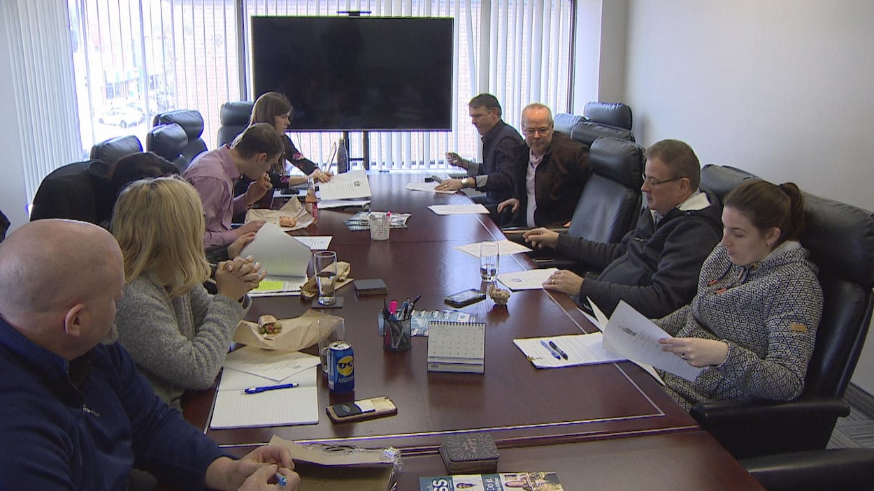 Une dizaine de personnes sont assises autour d'une table dans une salle de réunion.