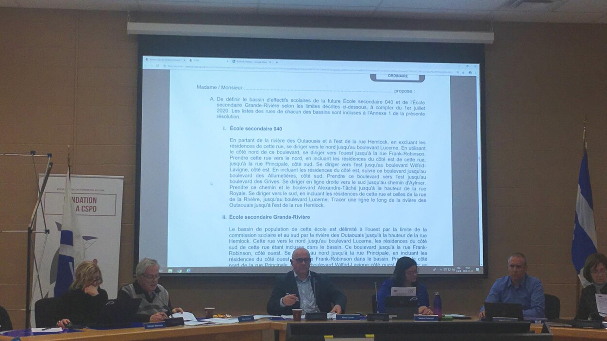 Six personnes assises à longue table devant une toile sur laquelle est projetée un document texte.