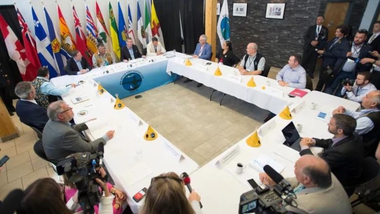 Les dirigeants sont assis autour d'une table rectangulaire.