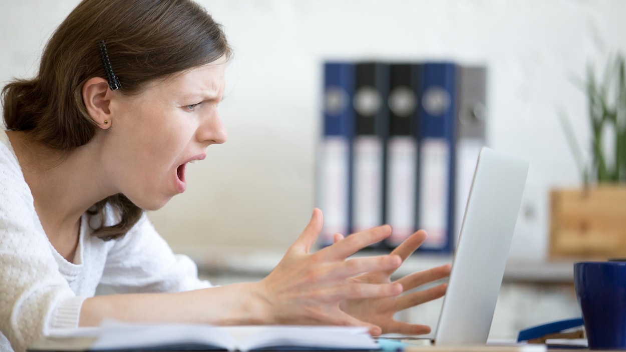 Une jeune femme assise devant un ordinateur portable affiche une expression de dégoût et de frustration. Une jeune femme assise devant un ordinateur portable affiche une expression de dégoût et de frustration.