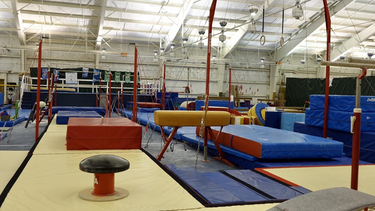 Des tapis de gymnastiques et d'autres appareils sont répartis sur deux terrains de tennis intérieurs.