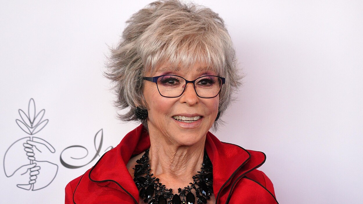 Rita Moreno souriante sur un tapis rouge.