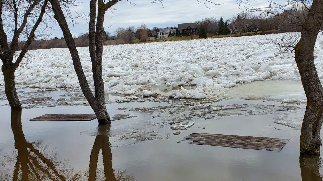 Une rivière couverte de glace avec deux tables de pique-nique englouties.