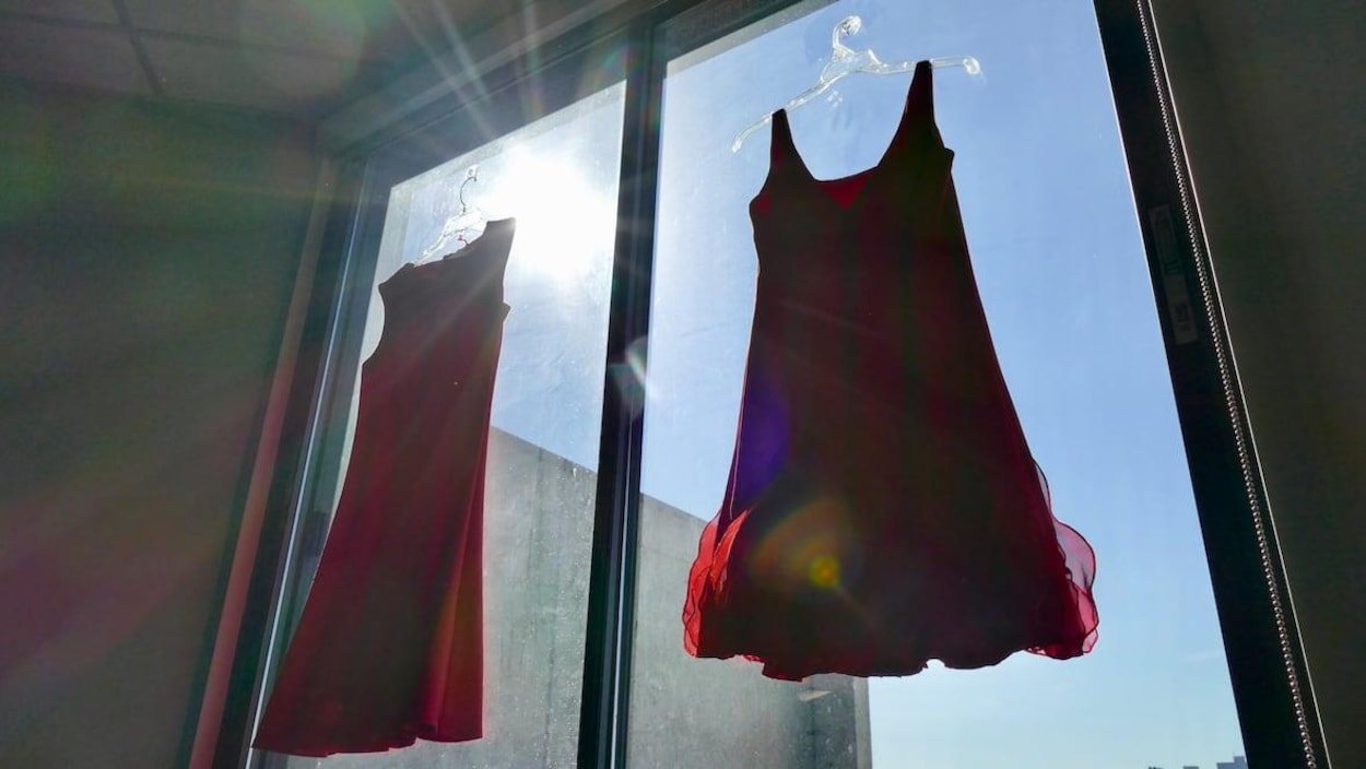 Deux robes rouges accrochées devant une fenêtre.