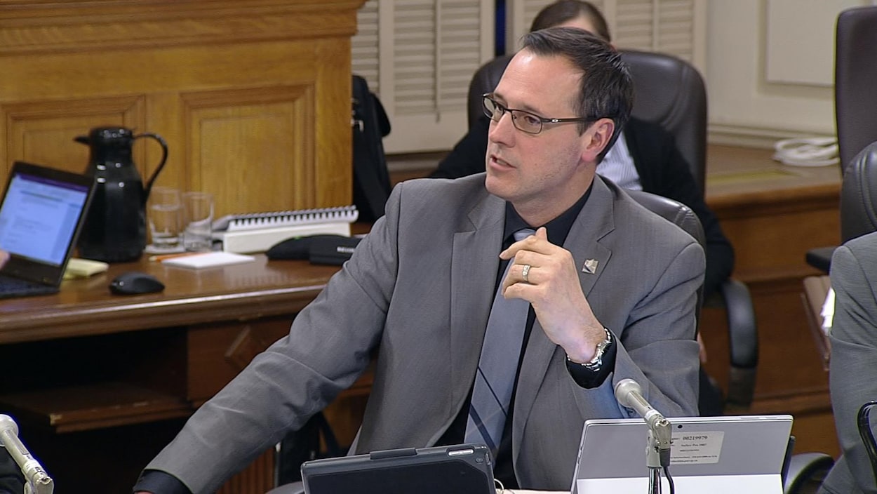Jean-François Roberge assis devant un micro et des écrans de tablettes.