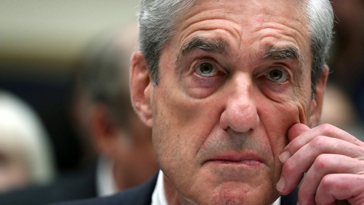 Plan rapproché de M. Mueller, qui se touche la joue.