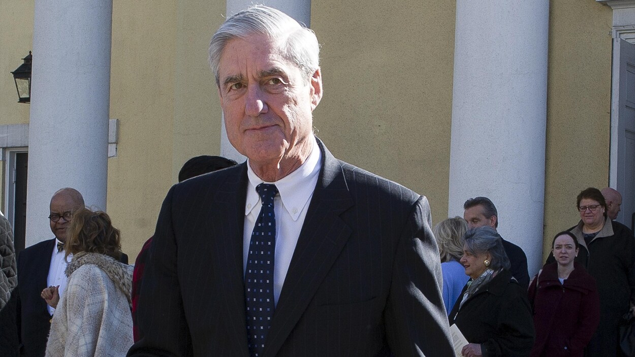 Robert Mueller est photographié à l'extérieur d'un bâtiment comportant de grandes colonnes blanches.