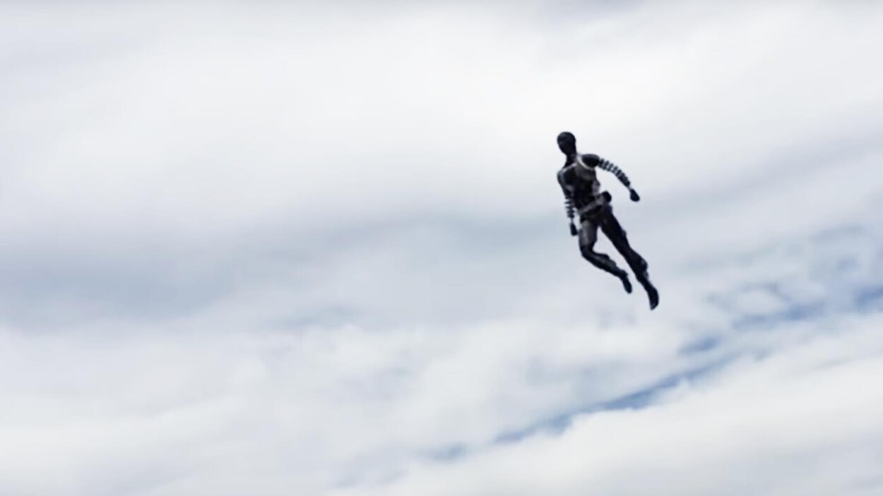 Une capture d'écran d'une vidéo montrant un robot adoptant une pose héroïque dans les airs. On peut voir un ciel nuageux derrière lui.