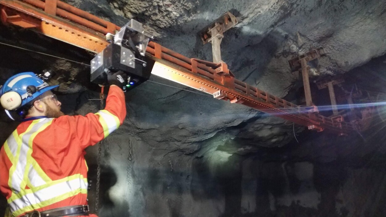 Un mineur qui touche un robot installé sur des rails
