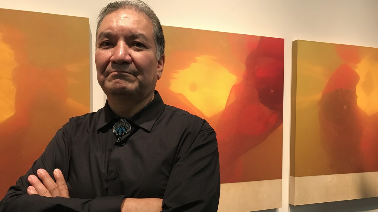 Un Autochtone pose devant des oeuvres d'art.