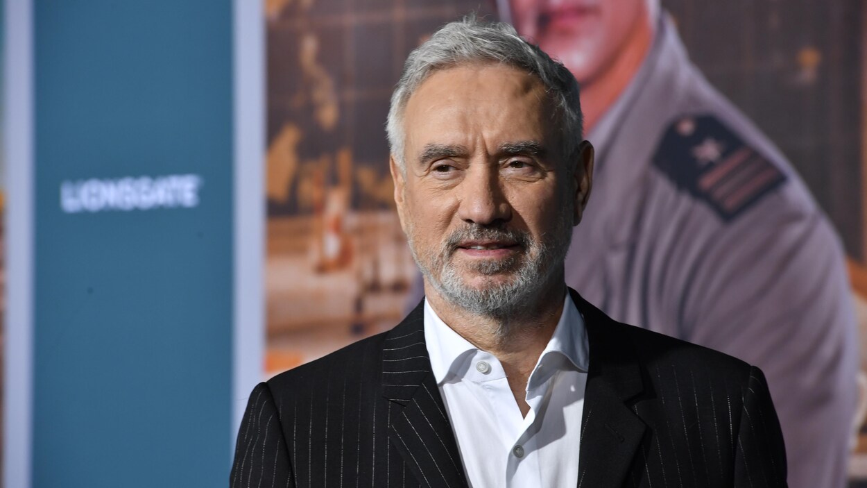L'homme aux cheveux gris porte un veston et une chemise.
