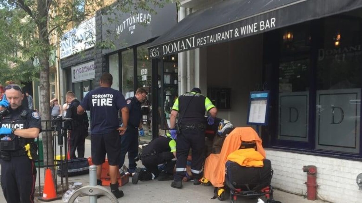 Des équipes de secouristes sont regroupées autour d'une personne étendue sur le trottoir.