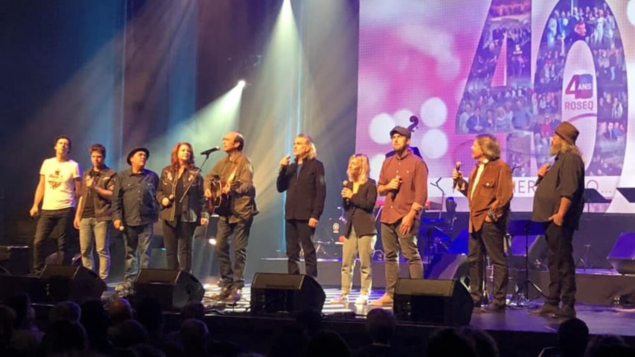 Une douzaine d'artistes chantent en coeur du scène.
