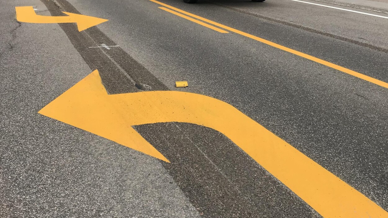 Des flèches peintes sur la chaussée indiquent que les automobilistes dans cette voie peuvent tourner à gauche ou à droite.