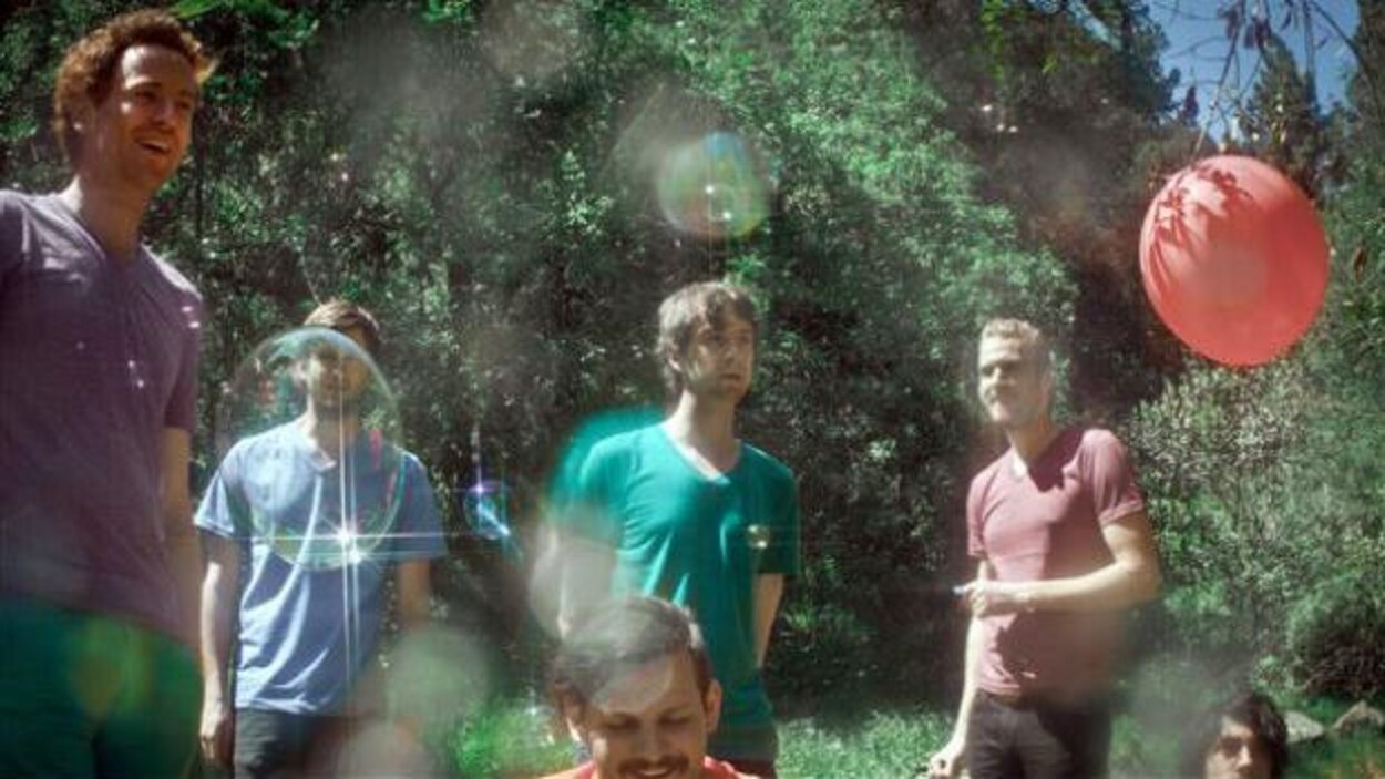 Six hommes sourient avec ce qui semble être une forêt bien verte derrière eux.