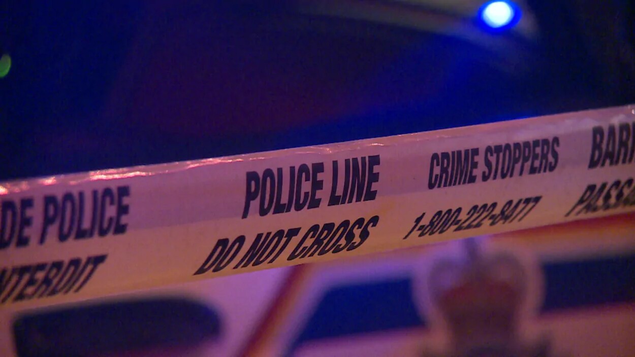 Un ruban jaune sur lequel on peut lire Police Line Do not cross ainsi que Crime Stoppers 1-800-222-8477.