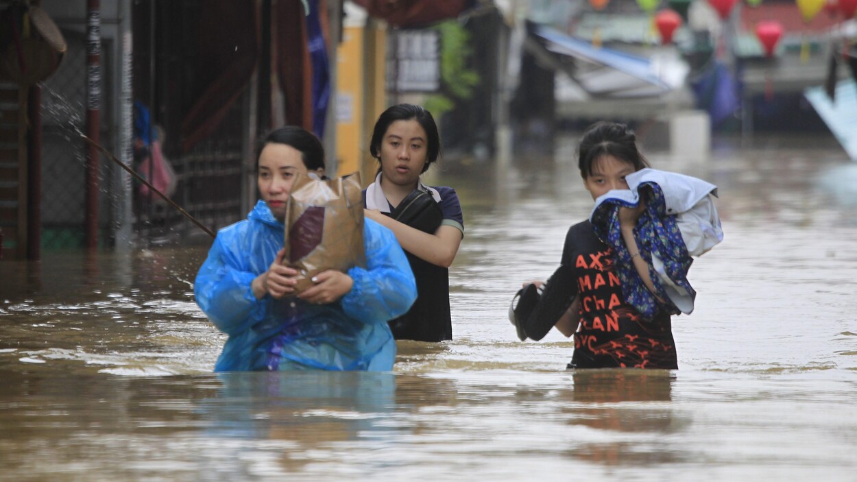 Des habitants avancent dans les rues inondées de l’ancienne ville de Hoi au Vietnam. Des habitants avancent dans les rues inondées de l’ancienne ville de Hoi au Vietnam.