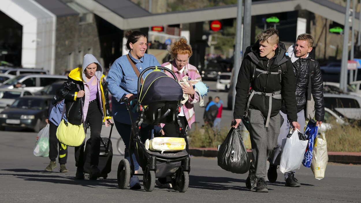 Un groupe de Russes marche avec leurs bagages.