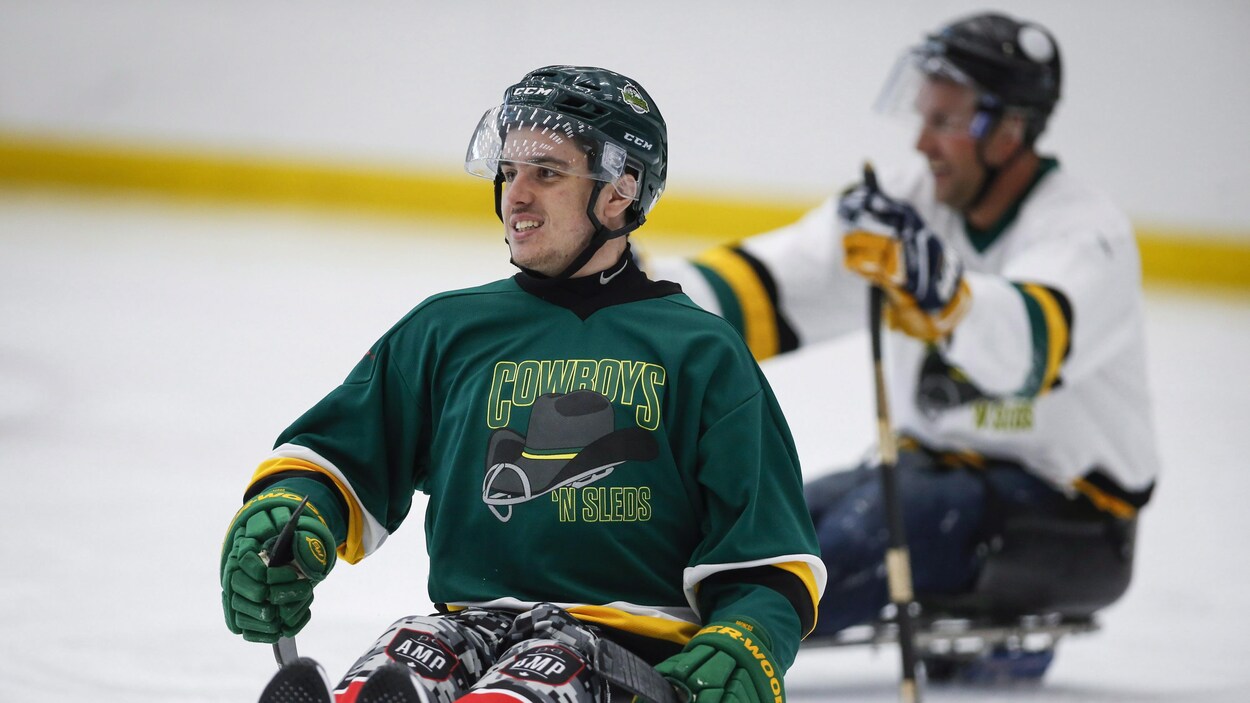 Ryan Straschnitzki porte un casque et joue au hockey sur luge avec des bâtons dans les mains Ryan Straschnitzki porte un casque et joue au hockey sur luge avec des bâtons dans les mains