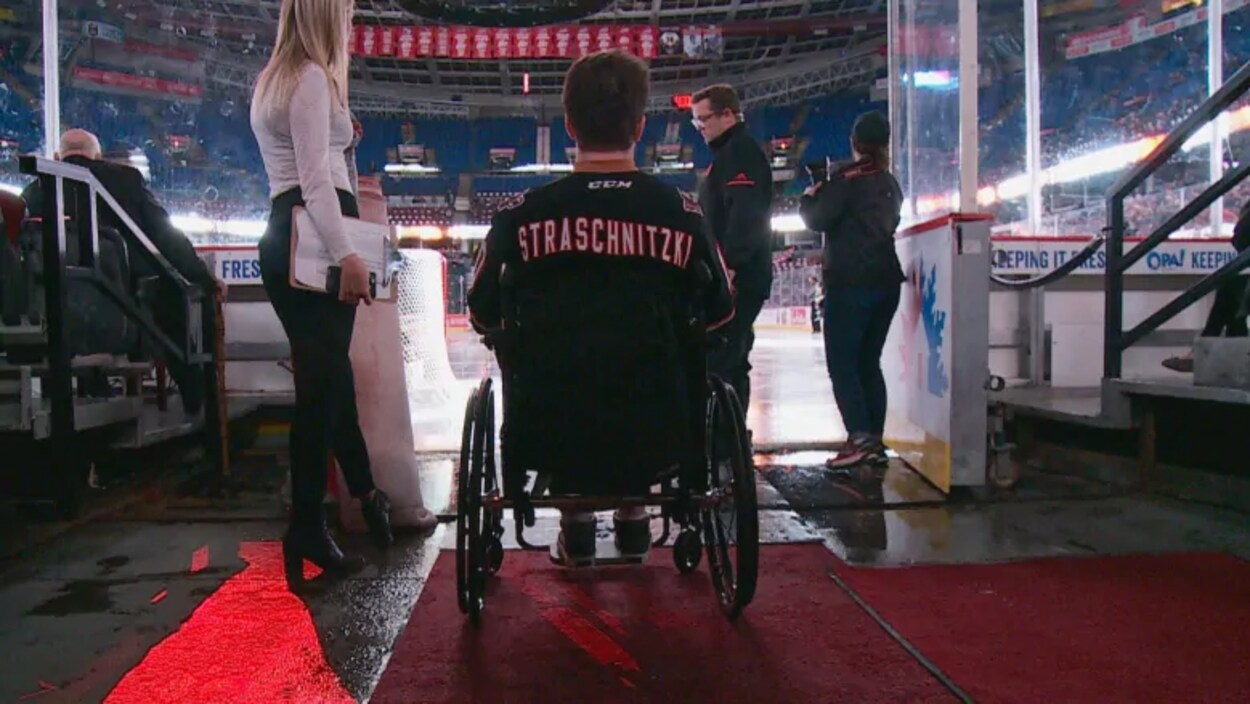 Ryan Straschnitzki en chaise roulante à l'entrée d'une patinoire.