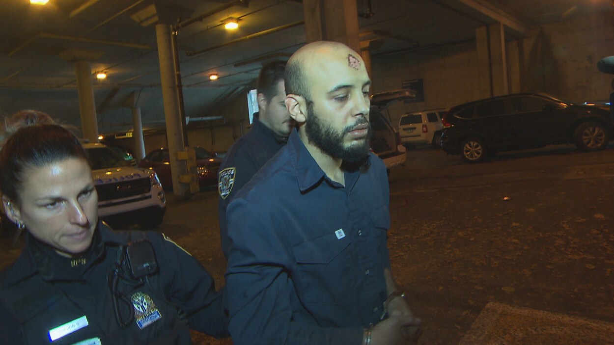 Saad Amine Habboub marche menoté et est escorté par deux policiers.