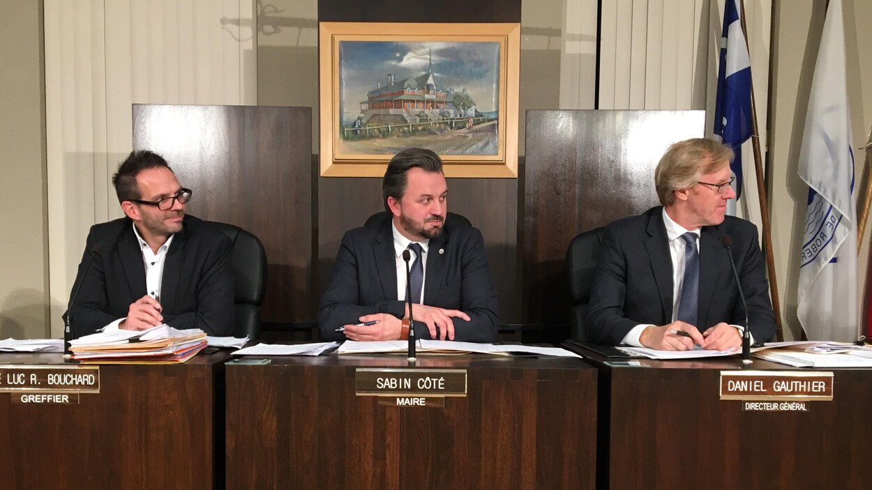 Sabin Côté, entouré du greffier et du directeur général lors d'une séance du conseil municipal.