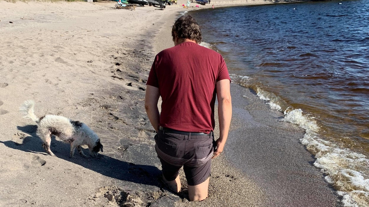 Un homme de dos avec les jambes enfoncées dans le sable.