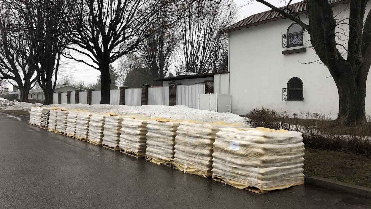 Des sacs de sable, sur des palettes de bois, déposées sans être utilisés sur une rue fantôme.