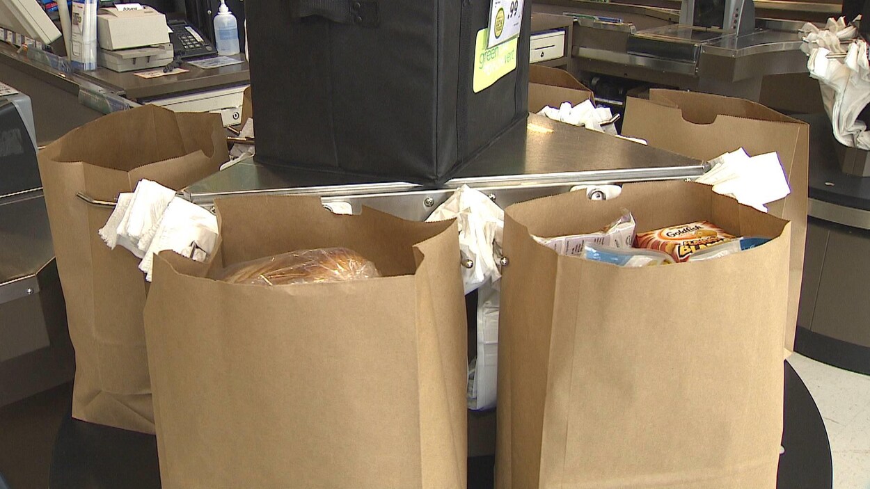 Des sacs en papier rempli d'aliments sur un tourniquet à l'épicerie.