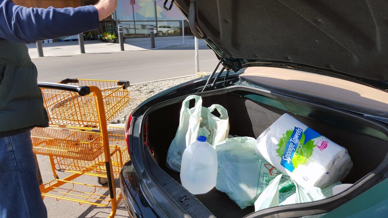 Une valise d'auto ouverte avec des sacs de plastique à l'intérieur, un rouleau d'essuie-tout et une cruche d'eau en plastique.