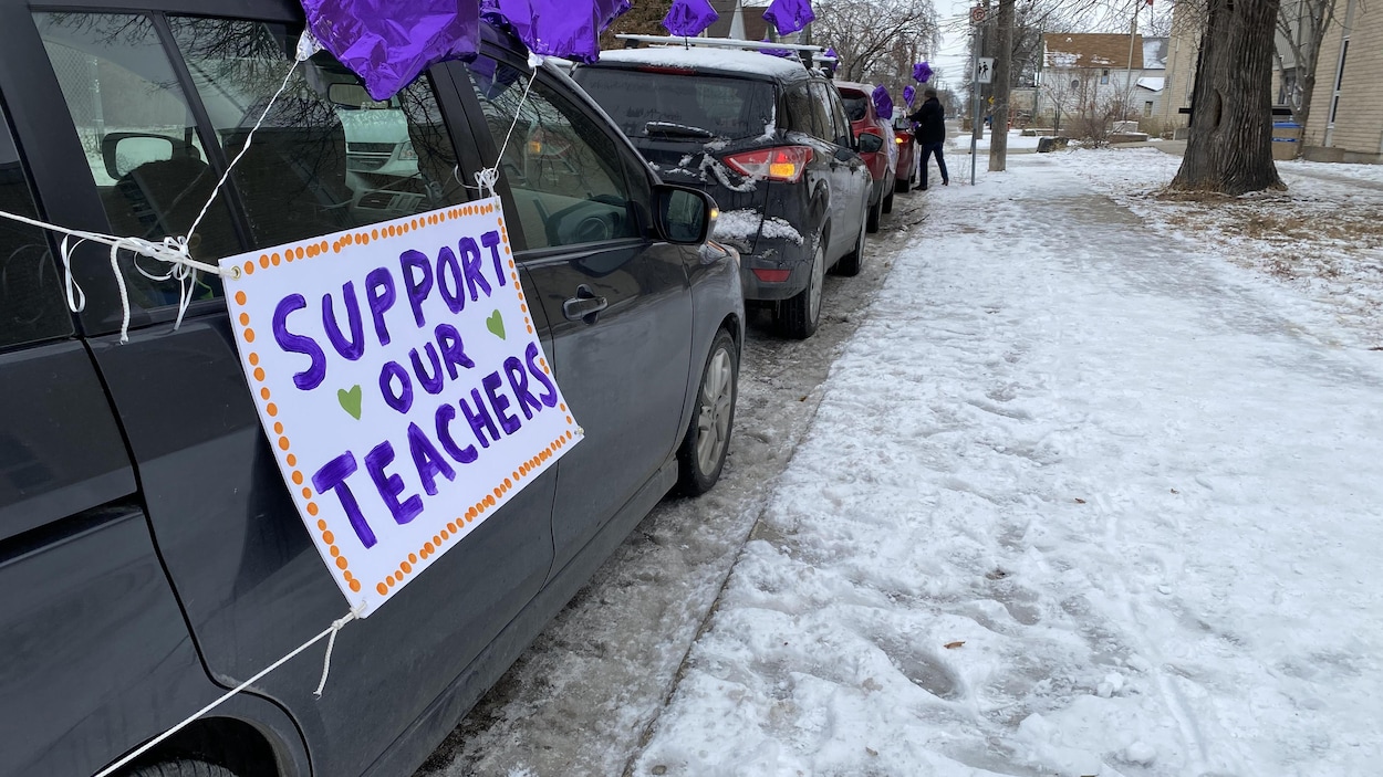 Un convoi de voitures est stationné devant une école.