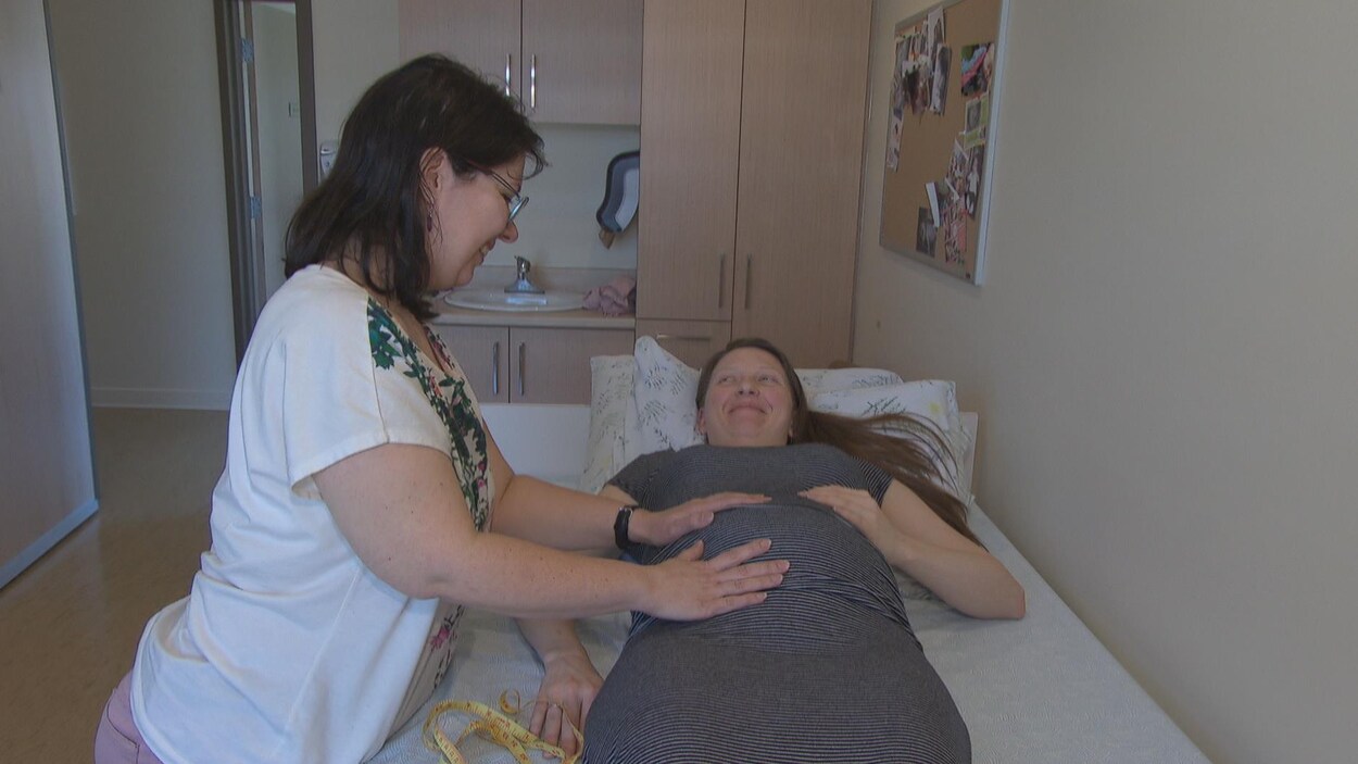 Une sage-femme examine une femme enceinte.