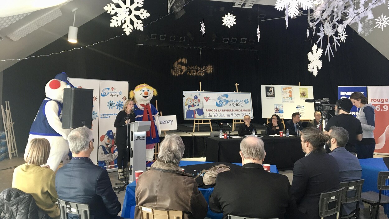 Une organisatrice est au micro pour donner les détails de la programmation aux gens présents à la conférence de presse.