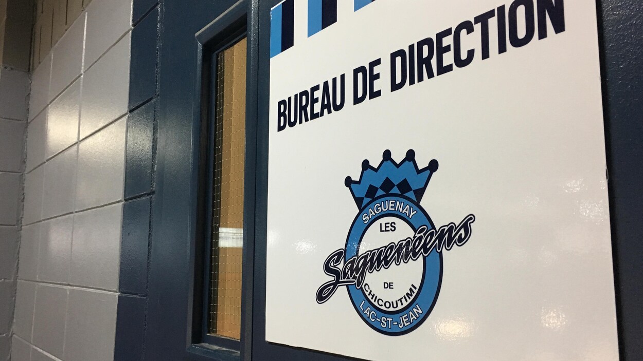 Une affiche avec le logo des Saguenéens de Chicoutimi est apposée sur une porte bleue.