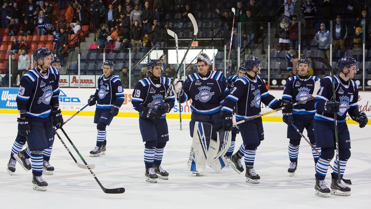 Des joueurs des Saguenéens de Chicoutimi se trouvent au centre de la patinoire.
