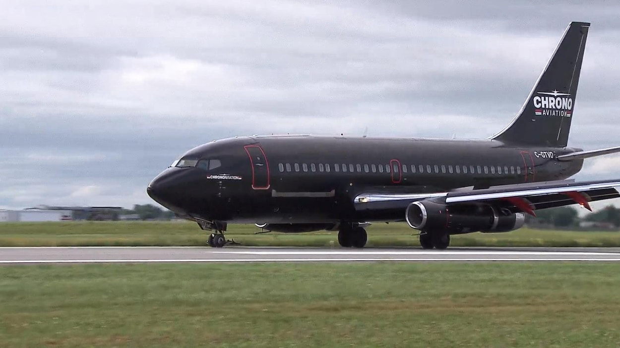 Un Boeing 737-200 de couleur noire roule sur la piste principale de l'aéroport de Saint-Hubert.