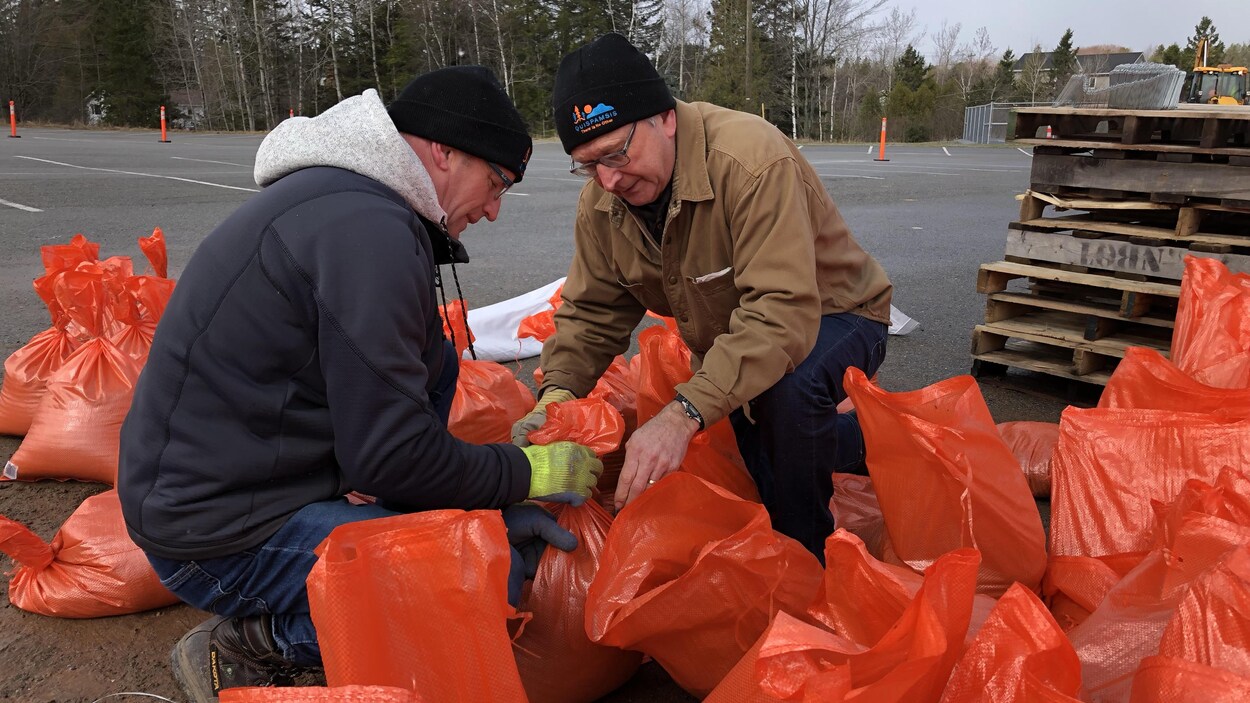 Blaine Higgs accroupi attache des sacs remplis de sable