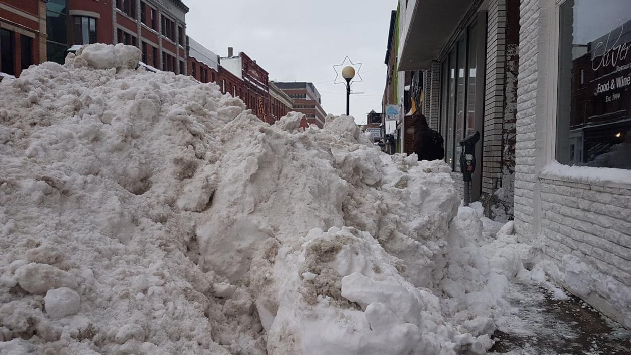 Un énorme monticule de neige bloque le trottoir devant le restaurant