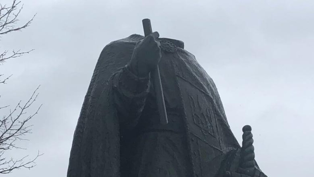 Une statue sans tête avec un ciel nuageux.